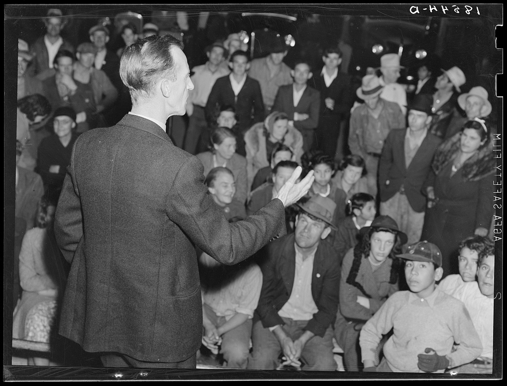 A night street meeting in Shafter, California, 1938, where an organizer for the United Cannery Agricultural Packing and Allied Workers of America addresses a crowd.